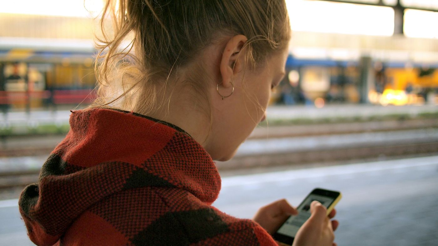 Young woman reading her phone on a train platform