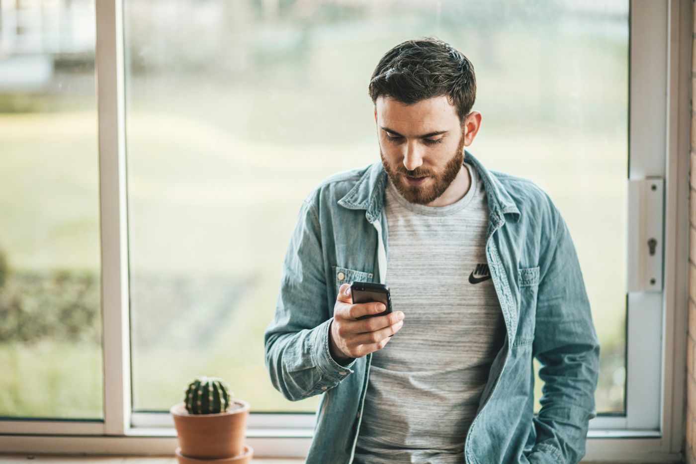 Man by a window reading a message on his phone